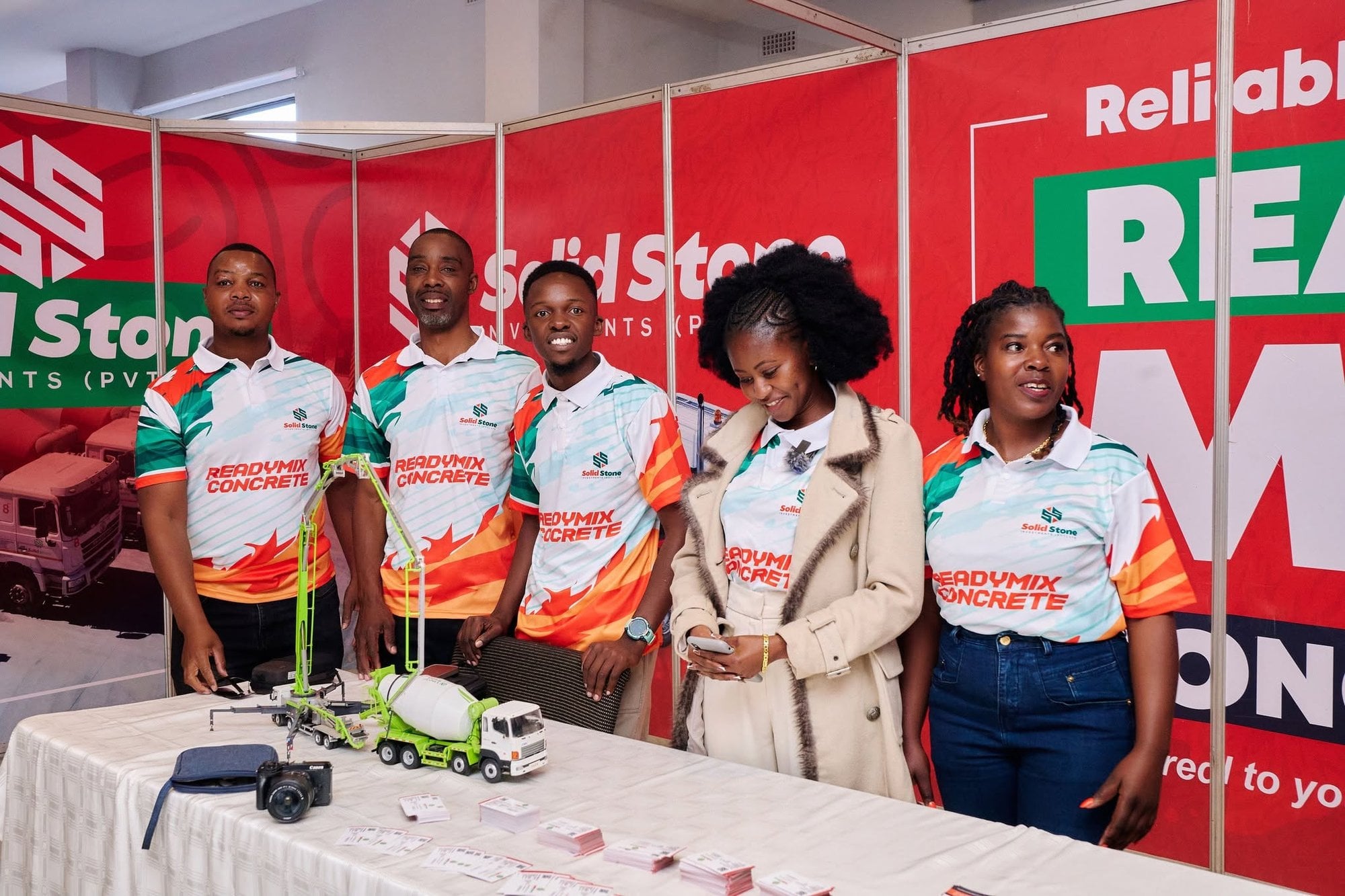 Five staff in matching branded sublimated golf shirts at an exhibition stand