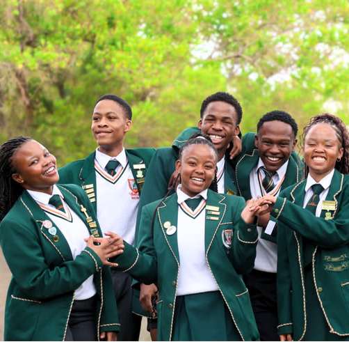 Students in green blazers laughing together for a school photo