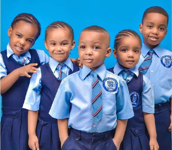Five young pupils in light blue shirts, ties and navy pinafores